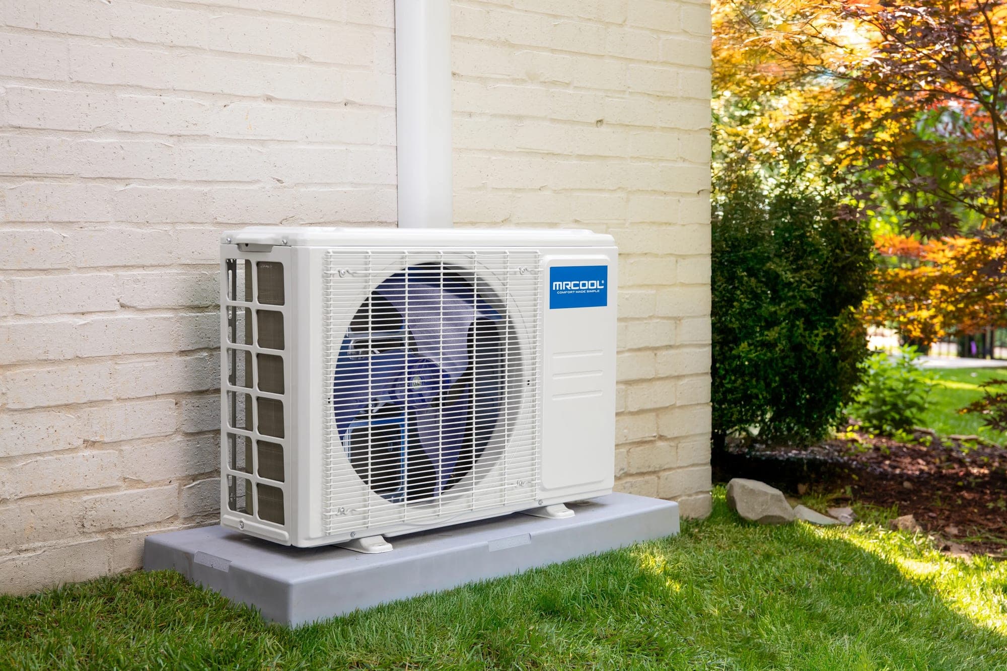 MRCOOL outdoor condenser on a ground pad beside a brick home